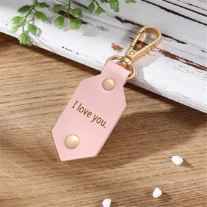 Pink leather photo keychain with gold metal clasp, detailed close-up shot showing surface engraving.