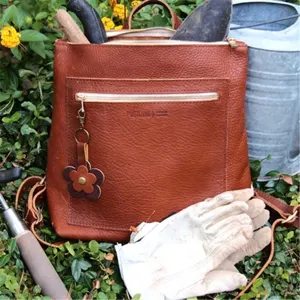 Zaino in pelle marrone con ciondolo a fiore e tasca frontale con zip, stile giardino.