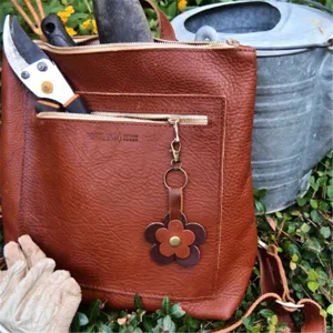 Borsa in vera pelle marrone con cerniera metallica e grazioso ciondolo a fiore per tutti.