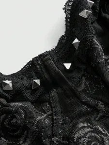 Primo piano dei dettagli del corsetto in pizzo gotico nero con borchie piramidali argentate.