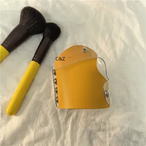 Gele lederen handgedragen make-up palet met doorzichtige PVC hoes en metalen drukkers.
