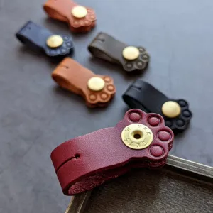 Close-up view of cute leather cat paw cable winder with snap button detail and vibrant colors.