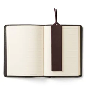 Close-up detail of dark brown PU leather bookmark placed neatly inside a lined notebook.