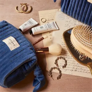 Velvet cosmetic pouch detail shot, blue portable makeup bag with brand logo and zipper ribbon design.
