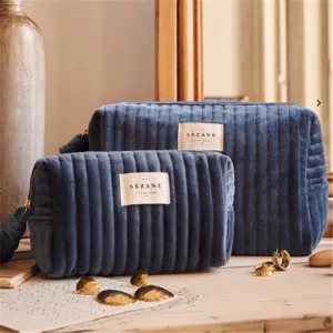 Blue velvet cosmetic bag set with vertical stripes and brand label for daily storage detail.