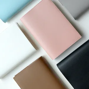 Close-up detail of minimalist PU leather notebook covers in multi colors for desk flat lay.