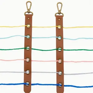 Vue détaillée d'une sangle organisateur de fil en cuir avec fermoirs métalliques et fils colorés.