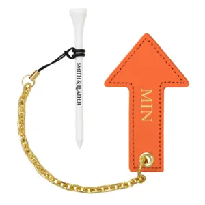 Golf tee holder detail view showcasing orange leather arrow tag and gold chain accessory.