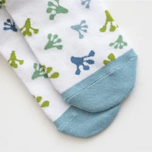 Nahaufnahme von niedlichen Socken mit Froschfuß-Muster und blauen Spitzen und Fersen.