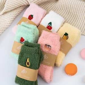 Close-up detail of cozy fuzzy plush winter socks with cute fruit embroidery and paper bands.