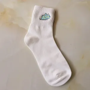 Close-up detail of white mid-calf cotton sock featuring cute embroidered blue dinosaur motif.