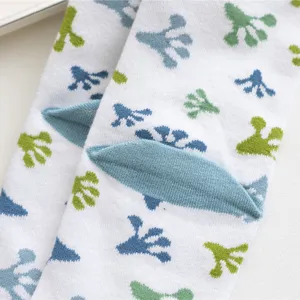 Nahaufnahme Detail von niedlichen grünen und blauen Froschmustern auf weißen Baumwollsocken.