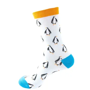 White cotton mid-calf socks detail with cute pixel penguin pattern and orange cuff design.