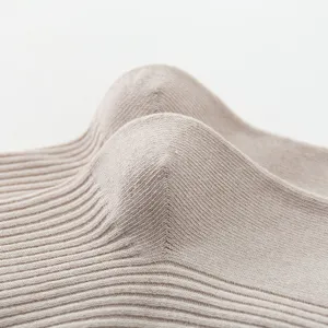 Nahaufnahme von gestrickten Rippsocken in warmer Beigefarbe mit feiner Textur.
