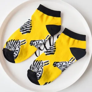 Close-up detail of yellow and black ankle socks featuring playful zebra head patterns.