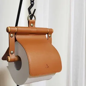 Hanging leather toilet paper holder with wooden stick design, stylish bathroom tissue storage.