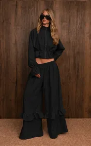 Black two-piece casual set with high-neck zip top and stylish ruffled wide leg pants.