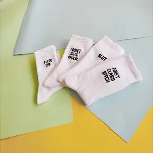 White casual crew socks featuring bold embroidered text designs, comfortable cotton blend daily wear.
