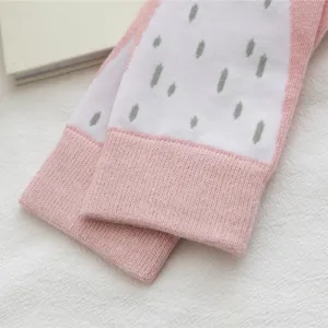 Close-up of knit mid-calf socks with pink cuffs and white textured pattern, soft fabric detail.