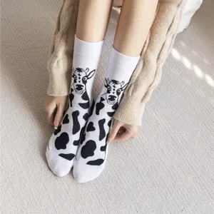 Detailed close-up showing cute black and white cow pattern mid-calf socks worn on feet.