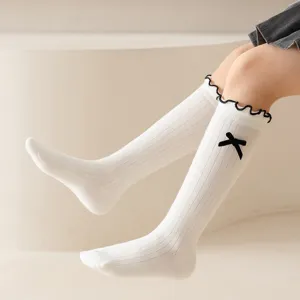 Sweet Japanese style white knee high socks for girls featuring cute black bow and ruffles.