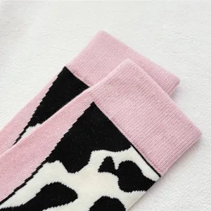 Close-up detail of cute pink cuff black white cow print knit socks comfortable soft fabric.