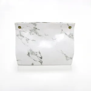 Close-up van de Scandinavische marmeren lederen tissue box hoes met metalen knopdetails.