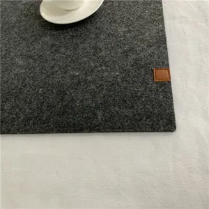 Primer plano detallado de la textura del mantel individual de fieltro gris oscuro con etiqueta.