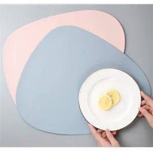 Close-up of irregular leather placemat set with white ceramic plate and fresh lemon.