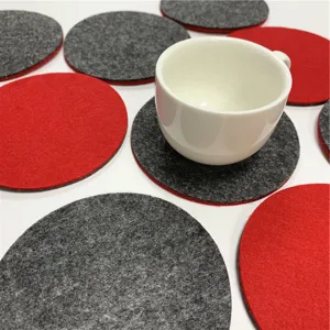Detailansicht der roten und grauen runden Filzuntersetzer mit weisser Tasse auf Tisch.