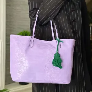 Élégant sac cabas en cuir texturé croco violet avec charmant pendentif palmier vert.