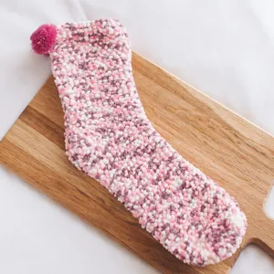 Detail shot of fluffy pink coral fleece sleeping socks with cute pom-pom, soft winter floor sock detail.