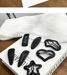 Primer plano detalle de pinzas para el cabello negras con purpurina en formas de corazón.