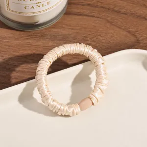 Beige pleated satin hair scrunchie with elastic rubber band, simple and elegant daily hair accessory.