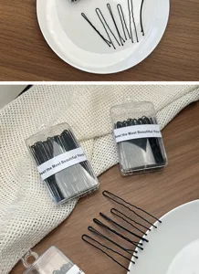 Black U-shaped hair pins and bobby pins set in clear boxes for professional styling and buns.