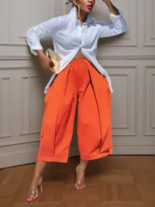 Detail view of stylish solid color wide leg cropped trousers worn with a chic white shirt.