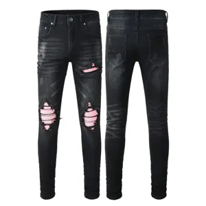 Detail view of men's black washed skinny ripped jeans featuring stylish pink patch details.