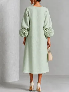 Close-up view of the 3D floral lantern sleeves and linen texture on this green dress.