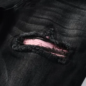 Black distressed denim jeans detail showing unique pink patch design, casual washed style pants.