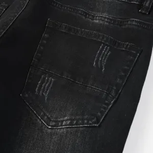 Close-up detail of black distressed denim jeans back pocket showing casual washed style texture.