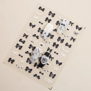 Gedetailleerd overzicht van 5D in reliëf gemaakte zwart-witte strik parel nail art stickerblad.
