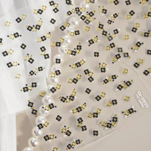 Close-up detail of 5D gold black clover nail art stickers featuring elegant floral embossed design.