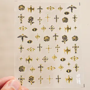 Detail shot of 5D embossed gold and black gothic cross nail stickers, sheet display.