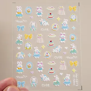 Close-up detail of 5D embossed cute rabbit nail art stickers with bows and cakes on clear sheet.