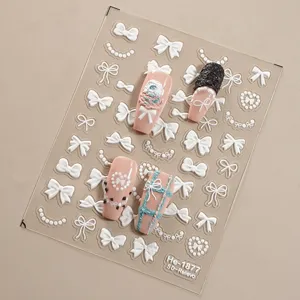 Close-up of 5D embossed nail art stickers featuring white bows and pearl details on clear sheet.