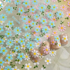 Close-up detail of 3D floral nail art stickers with cute daisy patterns and fake nail tips.