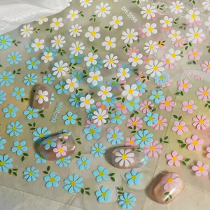 Detailed close-up of 3D daisy nail stickers featuring cute white, blue, and pink flower art.