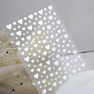 Detail view of 3D white heart nail art stickers with clear transparent adhesive sheet.
