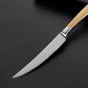 Gros plan détaillé d'un couteau à steak en acier inoxydable avec manche texturé doré.