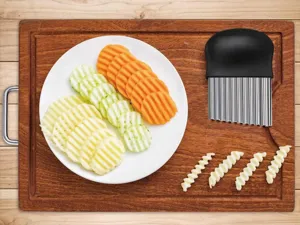 Stainless steel crinkle cutter kitchen tool potato slicer detail view on wood board